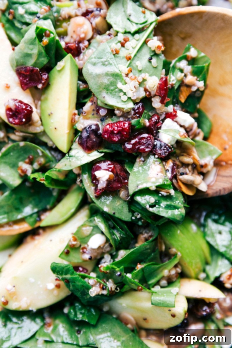 A large serving bowl filled with a thoroughly mixed Quinoa and Almond Salad, generously coated with dressing and ready to be served, highlighting the fresh, vibrant ingredients.