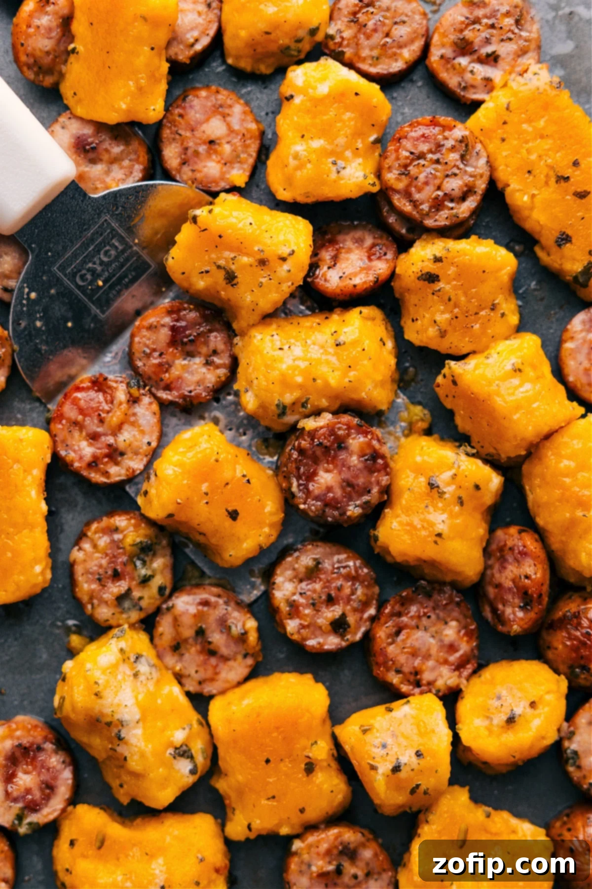 Sheet pan with roasted sweet potato gnocchi and Italian chicken sausage, ready to be tossed with pesto
