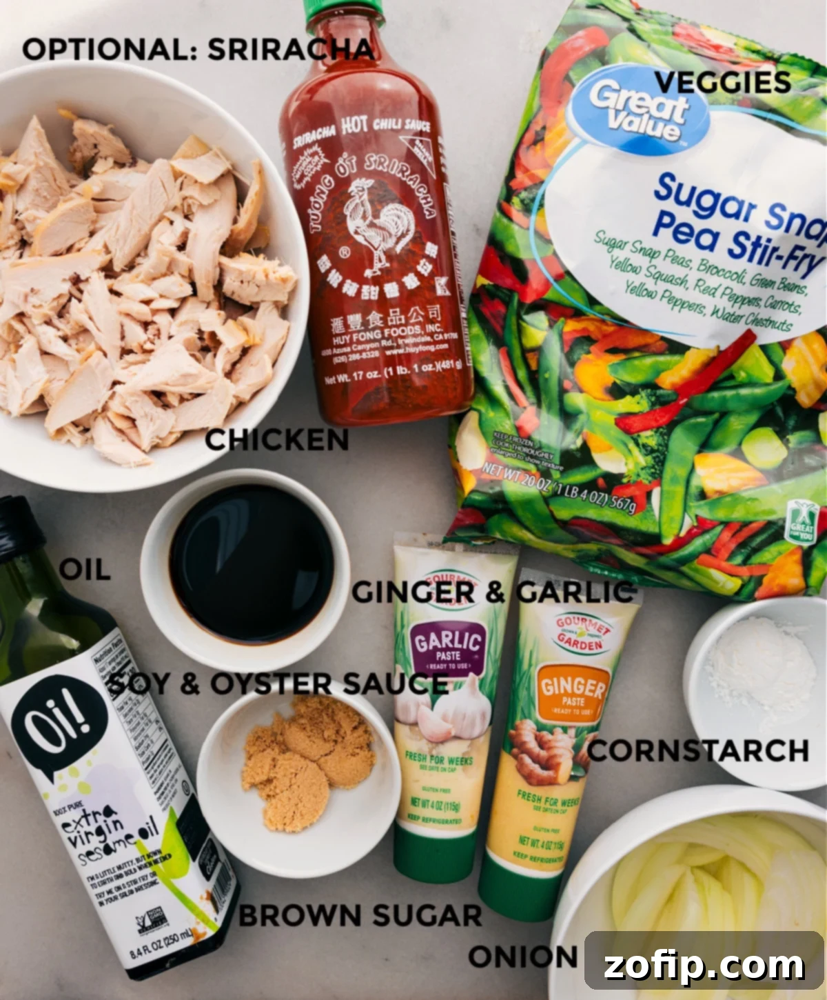 Organized ingredients for Rotisserie Chicken Stir-Fry, including thinly sliced onion, a vibrant frozen mixed vegetable blend, shredded rotisserie chicken, and the components for the homemade stir-fry sauce laid out for easy assembly.