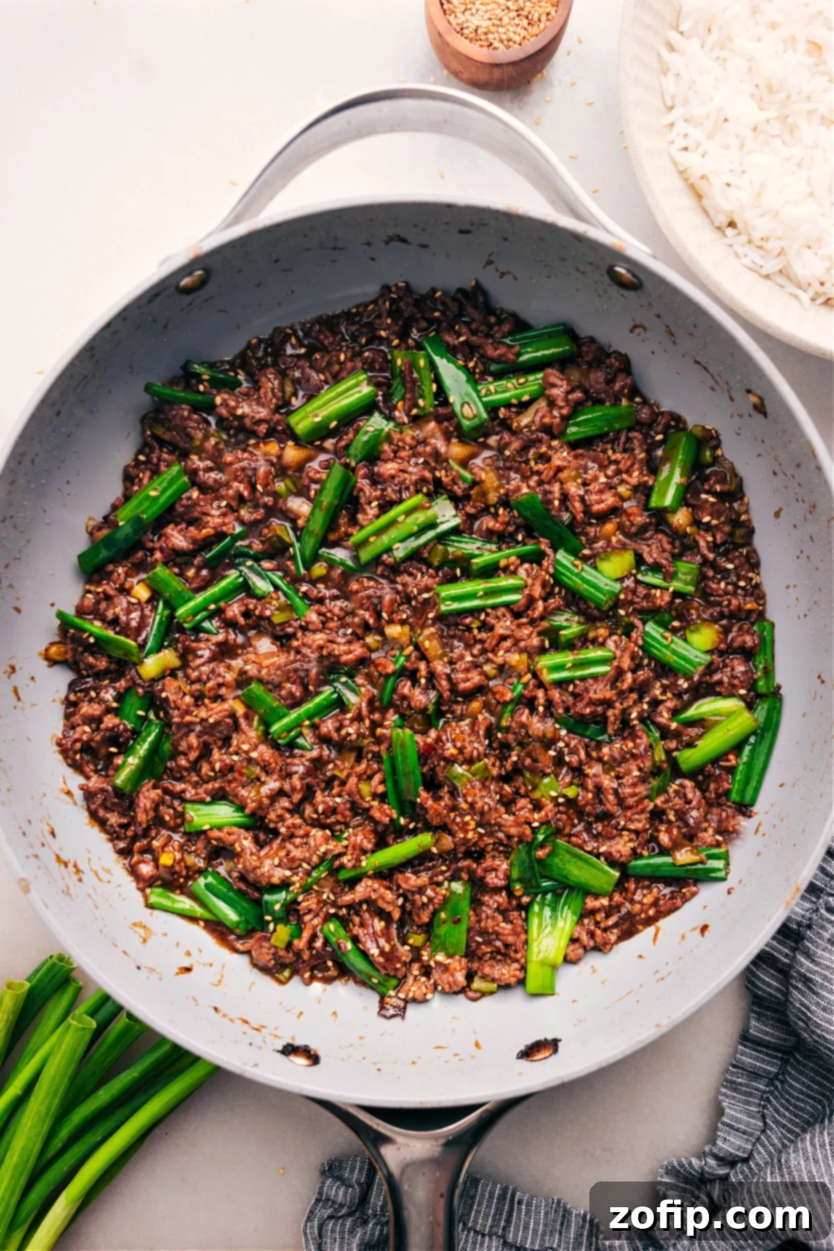 A large pot of Mongolian Ground Beef, rich with sauce and green onions, perfectly cooked and ready to be served over white rice for a satisfying meal.