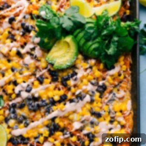 Loaded Sweet Potato Nachos 2 A close-up of a serving of Sweet Potato Nachos, piled high with melted cheese, black beans, corn, avocado, and chili-lime sauce.