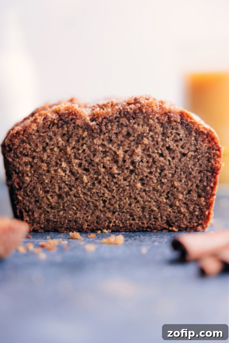 A perfectly baked loaf of Applesauce Bread, golden brown with a sugary crust, sliced and ready to be enjoyed with a cup of coffee.