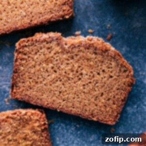 A warm, freshly baked loaf of Applesauce Bread on a wire rack, with some slices cut and stacked, revealing its moist, tender interior.