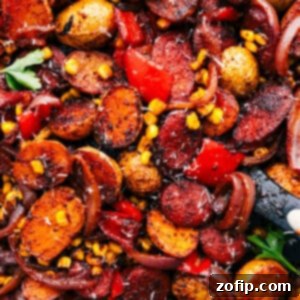 A vibrant, fully prepared sheet pan dinner featuring smoked sausage, crispy roasted potatoes, and colorful vegetables.