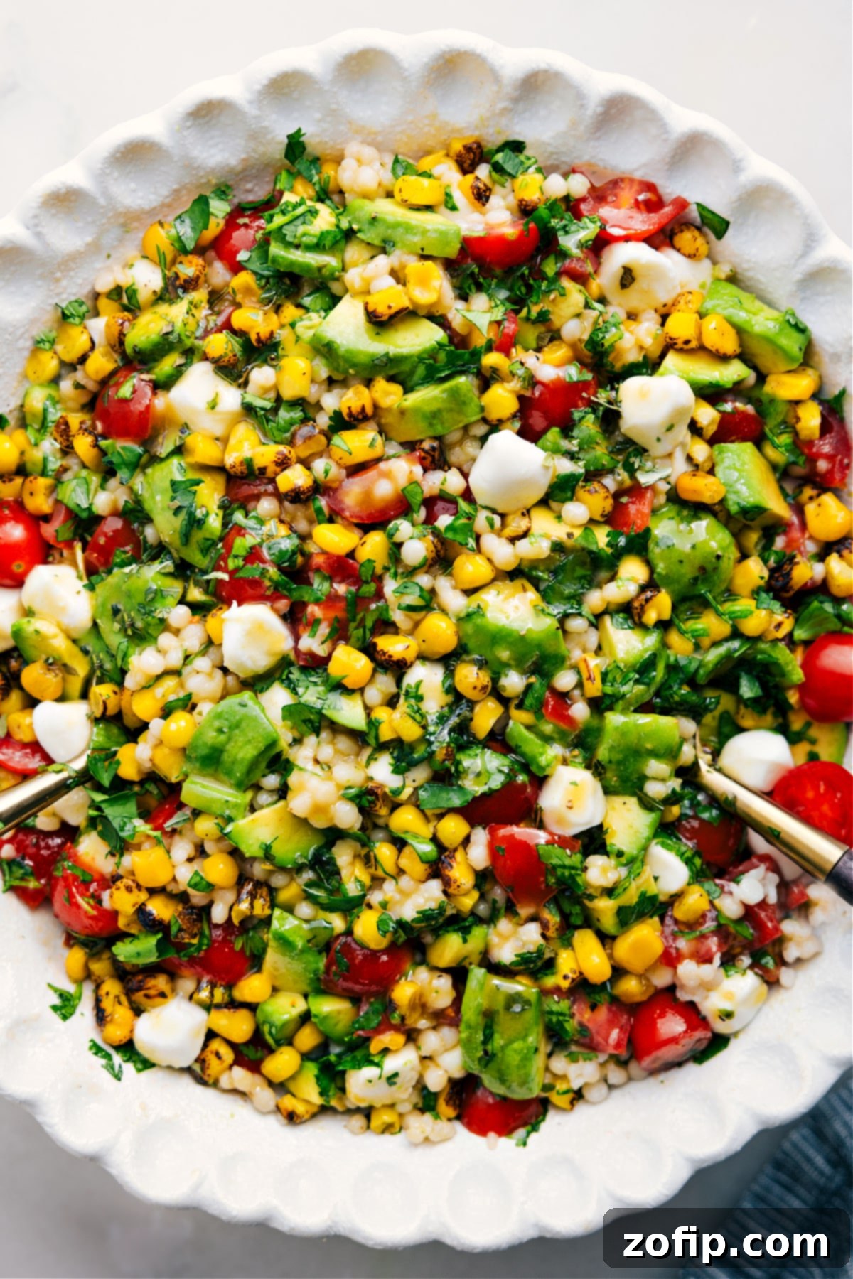 A big, delicious, and flavorful Summer Couscous Salad in a decorative bowl, dressed and garnished with fresh herbs, ready to enjoy as a perfect summer meal.