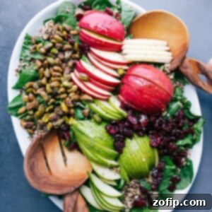A vibrant Quinoa Apple Salad, ready to be served, showcasing its fresh ingredients including greens, sliced apples, and various nuts.