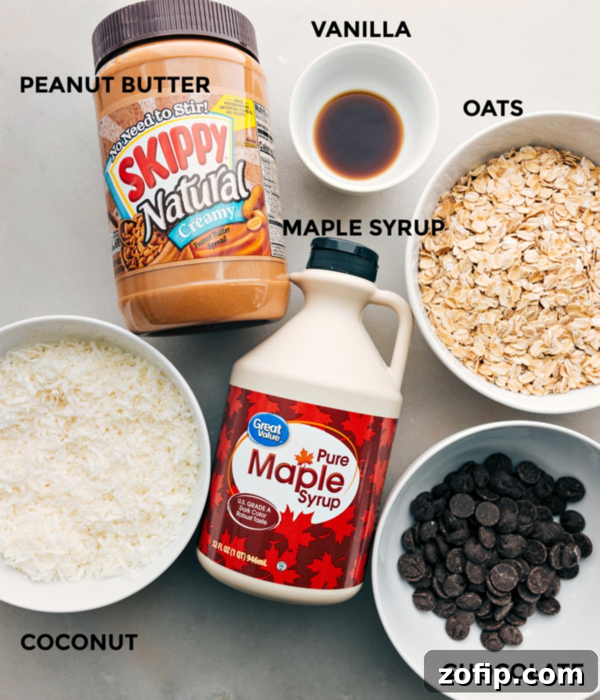 A vibrant selection of ingredients for Cookies and Cream Energy Bites, including peanut butter, vanilla extract, rolled oats, maple syrup, shredded coconut, and dark chocolate chips, all prepped and ready for assembly.