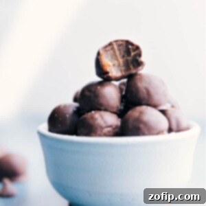 A close-up image of a perfectly round Healthy Chocolate-Covered Date Caramel with a sprinkle of sea salt on top, showcasing its delicious texture.