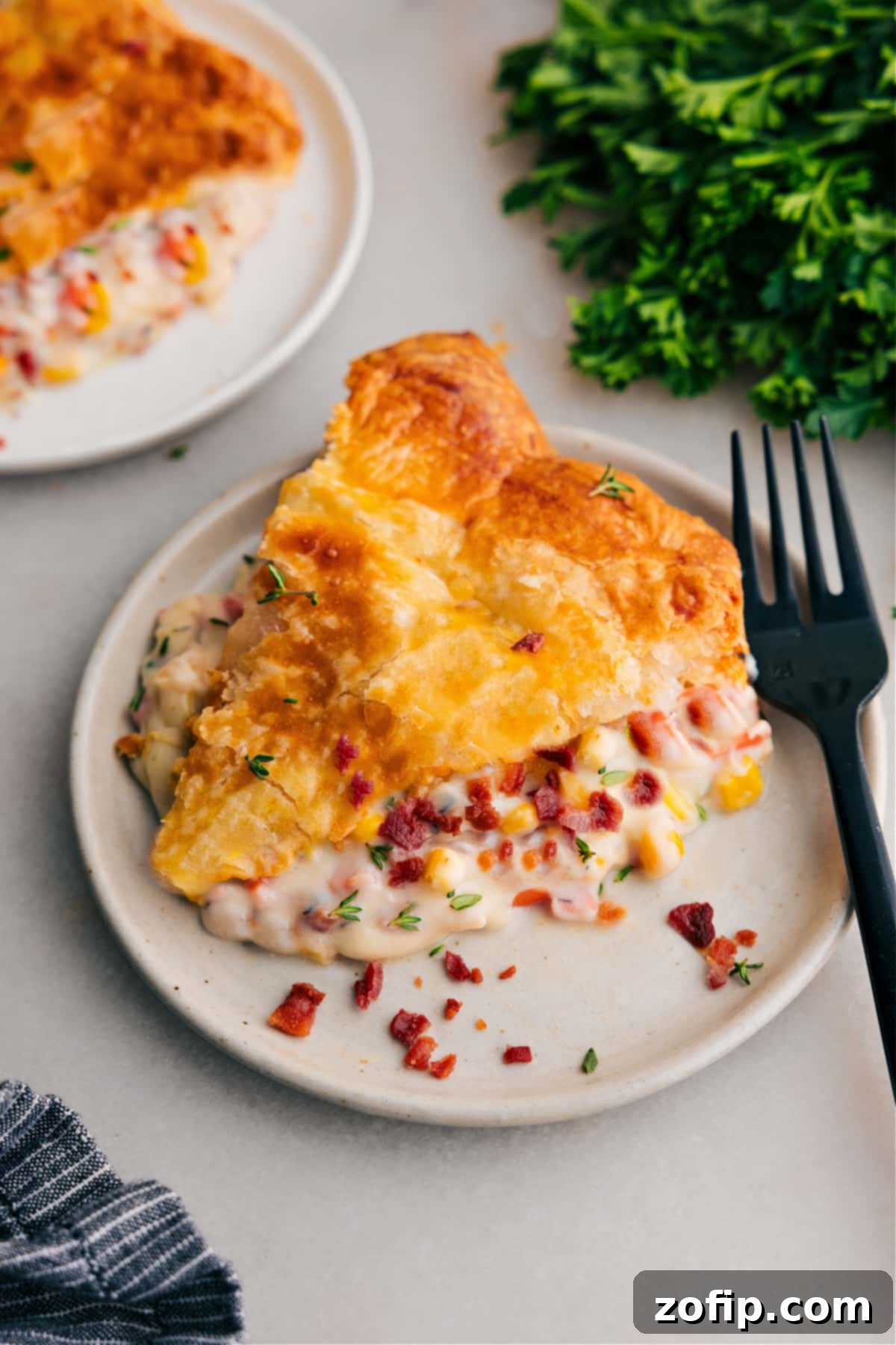 A golden-brown slice of Corn Chowder Pot Pie, rich with filling, served on a white plate, ready to be savored.