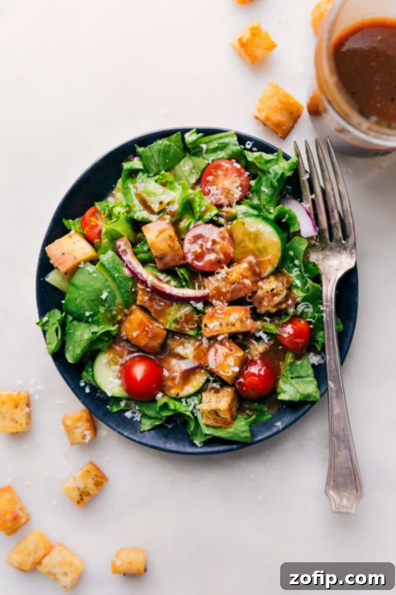 Overhead shot of a fresh green salad generously coated with homemade Balsamic Vinaigrette, showcasing its appealing texture and perfect coverage.