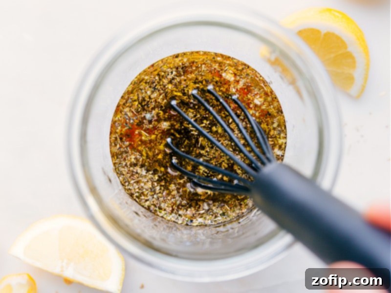 Image of the Greek Salad Dressing being vigorously whisked together in a bowl, showcasing the emulsification process.