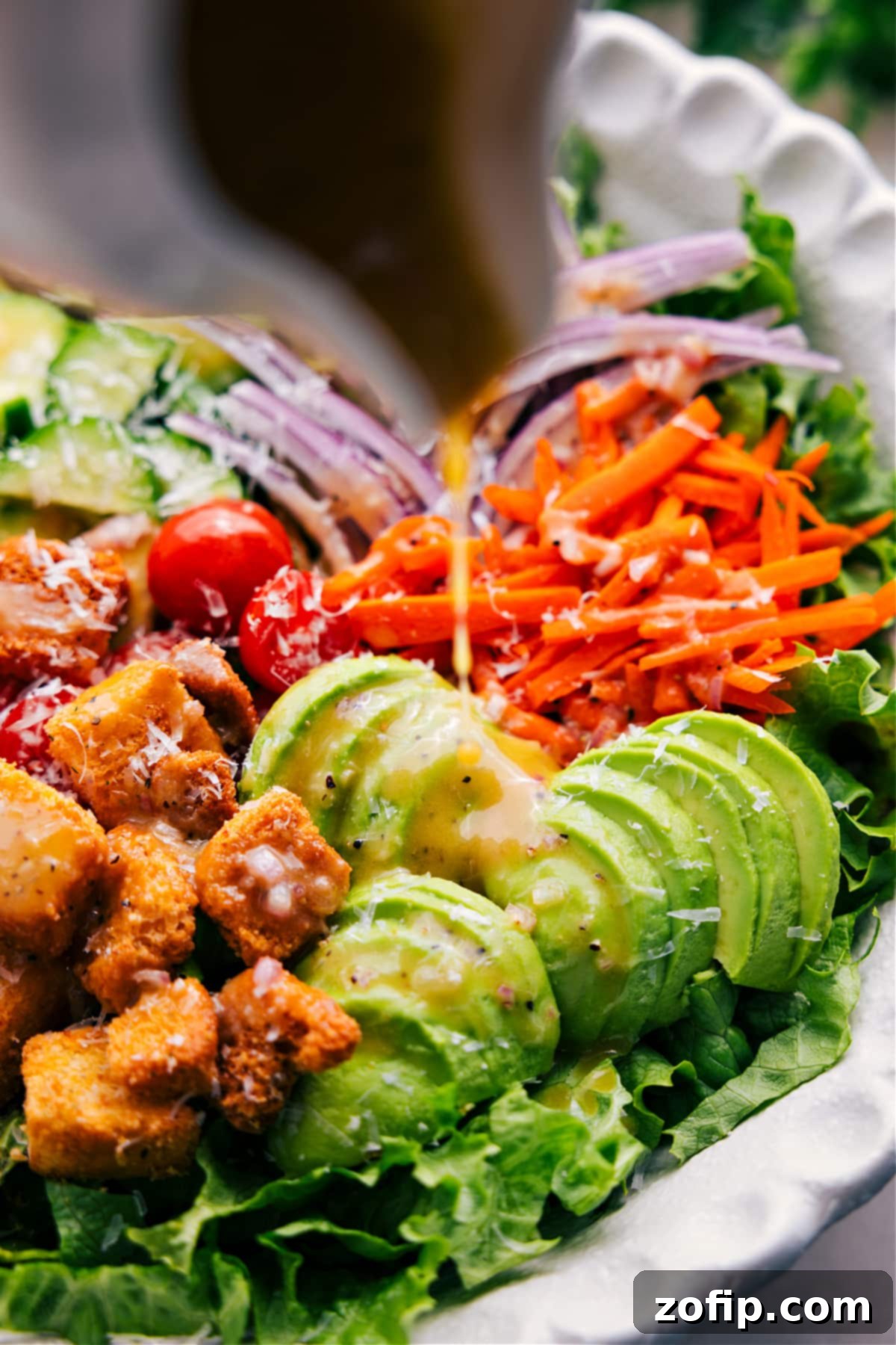 Drizzling the homemade vinaigrette dressing over a freshly prepared garden salad in a large bowl, ready to be tossed and served.
