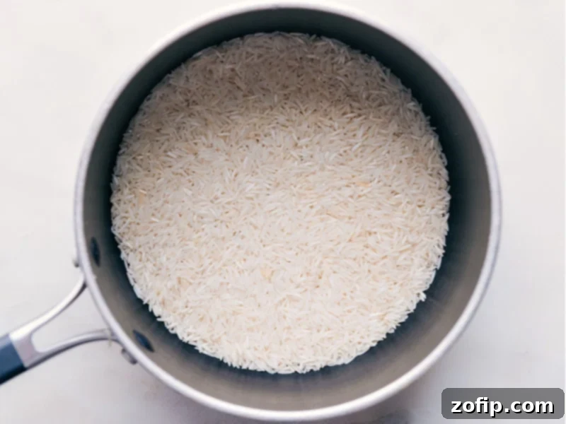 How To Make Coconut Rice Basmati rice being added to a pot, ready for cooking with coconut milk.