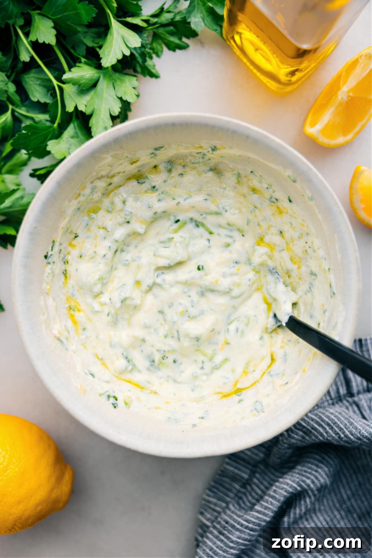 The Best And Easiest Tzatziki Sauce A bowl of creamy, delicious Tzatziki Sauce, garnished with fresh dill and a slice of lemon, ready to be enjoyed.
