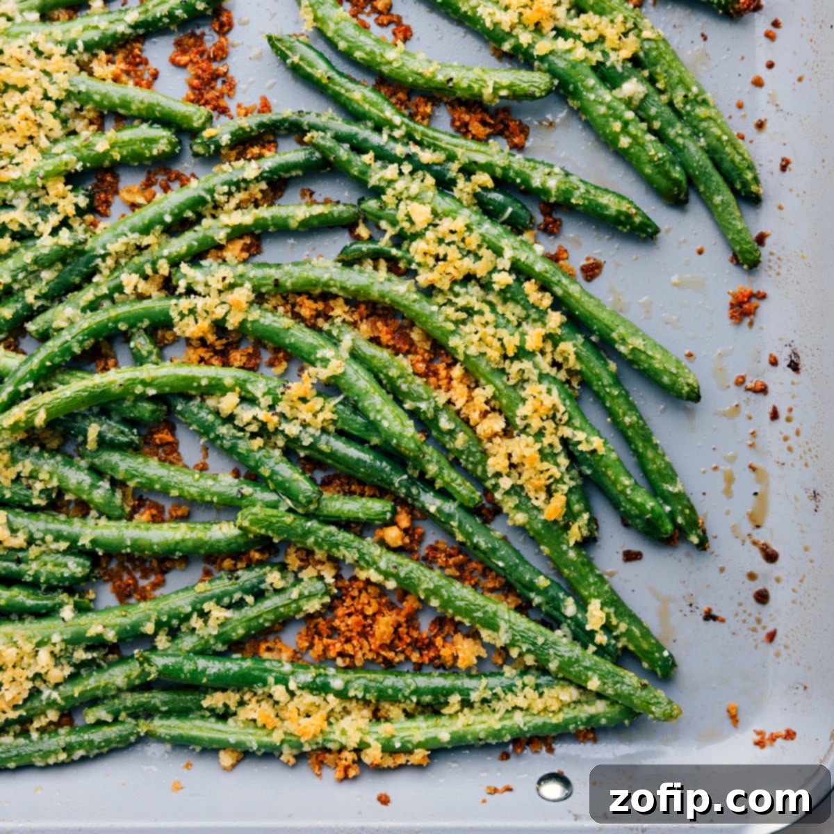 Easy And Delicious Roasted Green Beans Made Two Different Ways Two trays of roasted green beans, one simple seasoned and one with a crunchy panko and Parmesan coating, both looking perfectly crispy and delicious.
