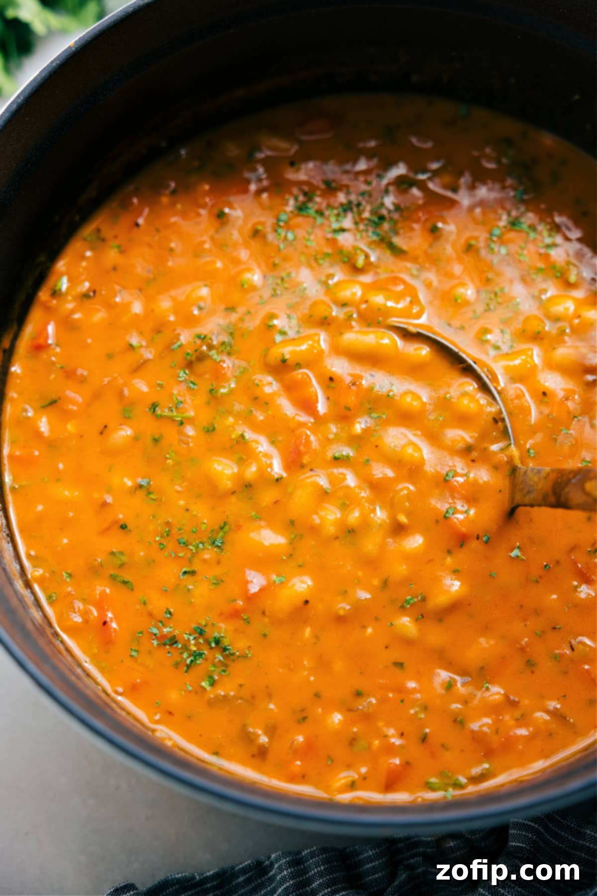 A steaming pot of White Bean Soup, ready to be served and enjoyed, garnished with fresh herbs.