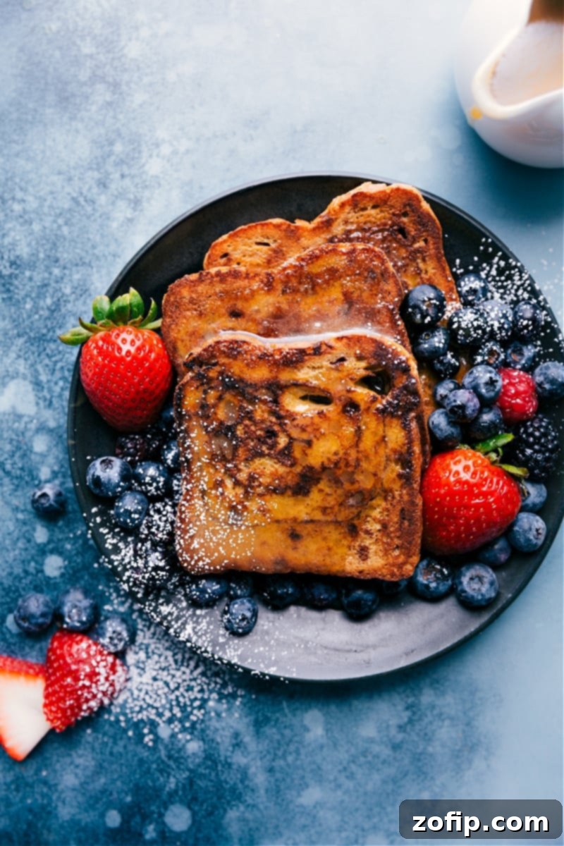 Cinnamon-sugar French toast, generously topped with whipped cream, fresh berries, and a simple yet decadent four-ingredient caramel syrup. This recipe is my cherished adaptation of a famous Utah bakery's signature dish. Golden cinnamon-sugar French toast with whipped cream, berries, and caramel syrup on a white plate