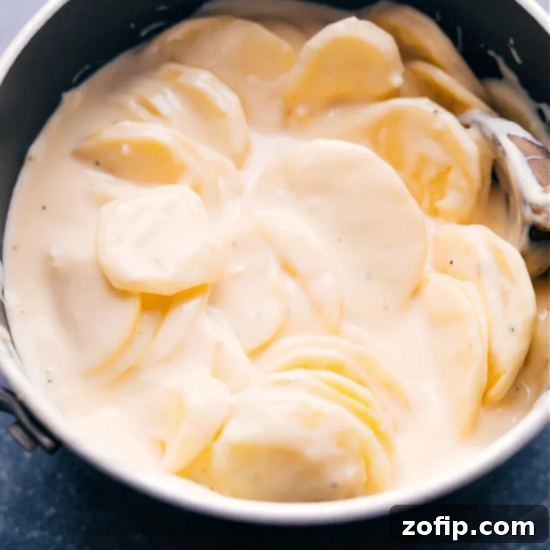 Up-close overhead view of the Crockpot Au Gratin Potatoes cooking inside the slow cooker, showing tender potatoes and melted cheese