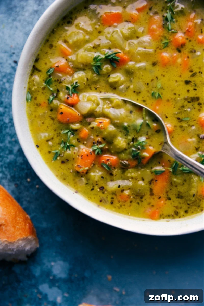 An up-close overhead image of a steaming bowl of Vegetarian Split Pea Soup with a spoon scooping out a creamy portion, highlighting its rich texture.