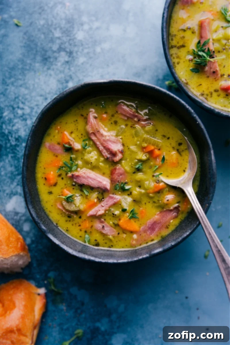 Overhead image of a bowl of thick, creamy Split Pea Soup with shredded ham and a sprinkle of fresh herbs.