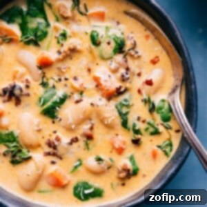 Hearty Sausage and White Bean Supper 3 A steaming bowl of creamy White Bean and Sausage Soup, garnished with fresh herbs and a sprinkle of Parmesan cheese.