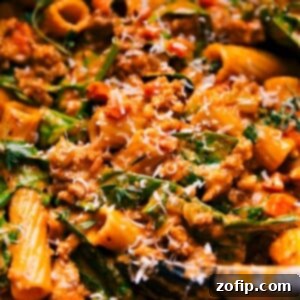 Sausage Rigatoni in a bowl with fresh herbs and grated Parmesan