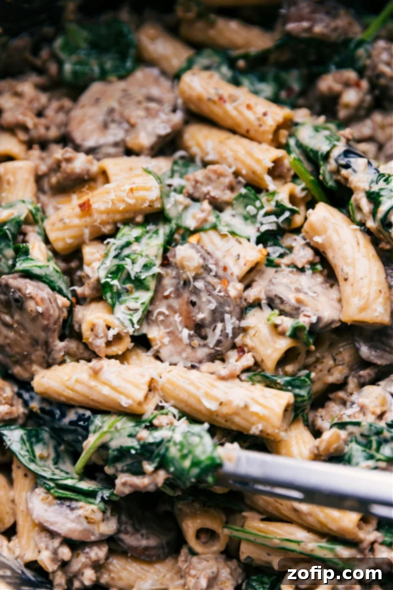 Finished Creamy Sausage and Mushroom Rigatoni in Pot Up-close overhead image of Creamy Sausage and Mushroom Rigatoni in a large pot, garnished with fresh herbs, showcasing the rich, creamy sauce clinging to the rigatoni pasta, sausage, and mushrooms.