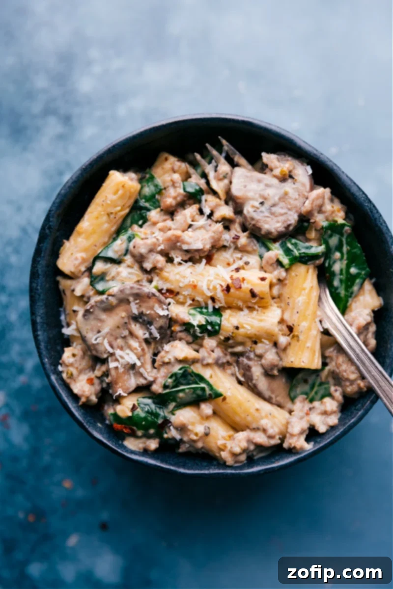 Delicious Creamy Sausage and Mushroom Rigatoni Serving Overhead image of Creamy Sausage and Mushroom Rigatoni served in a bowl, garnished with fresh parsley and grated Parmesan cheese, ready to be enjoyed.