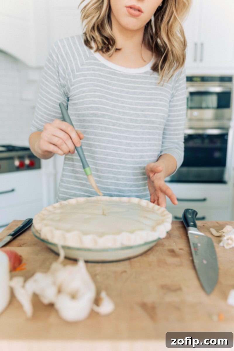 Doing the egg wash on the crust of this recipe, showing a golden pastry ready for the oven.
