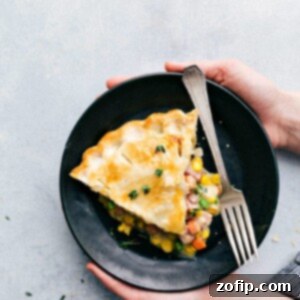 Holding a plate with this ham pot pie recipe, showing a slice ready to be enjoyed.