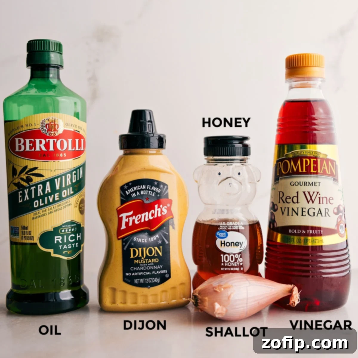 All the essential ingredients for a homemade honey-Dijon dressing: olive oil, Dijon mustard, honey, red wine vinegar, and fresh shallot.