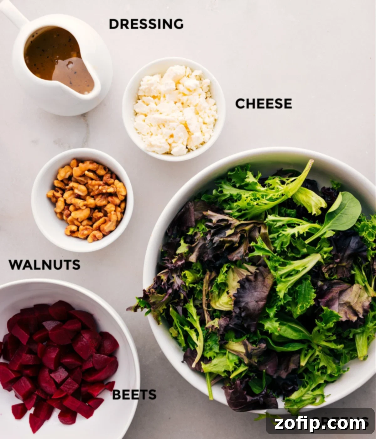 Fresh ingredients for Beet, Goat Cheese, and Walnut Salad, including vibrant mixed greens, cubed roasted beets, crumbled goat cheese, and toasted walnuts, all prepped and ready.