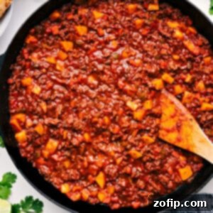 Savory Ground Meat Medley 3 A close-up of a serving of Mexican Picadillo, showcasing the rich tomato sauce, tender ground beef, and diced golden potatoes, garnished with fresh cilantro and a lime wedge.