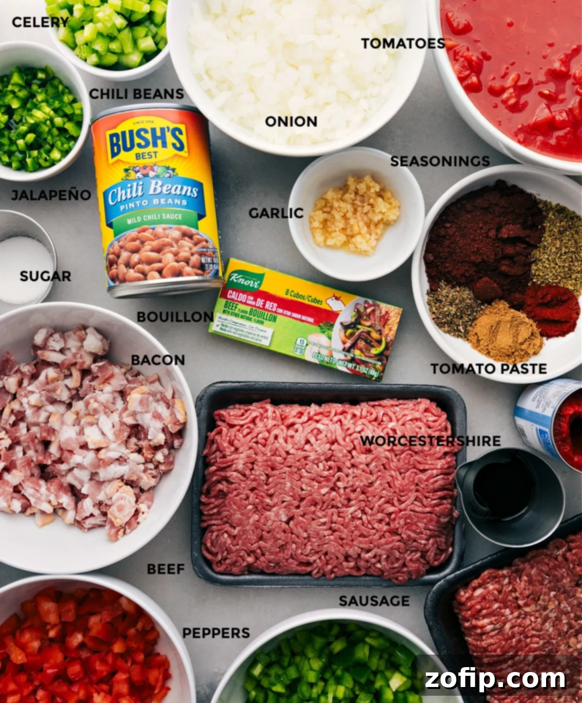 A selection of fresh ingredients including bell peppers, onions, celery, beans, ground beef, and spices, all prepped for making chili.