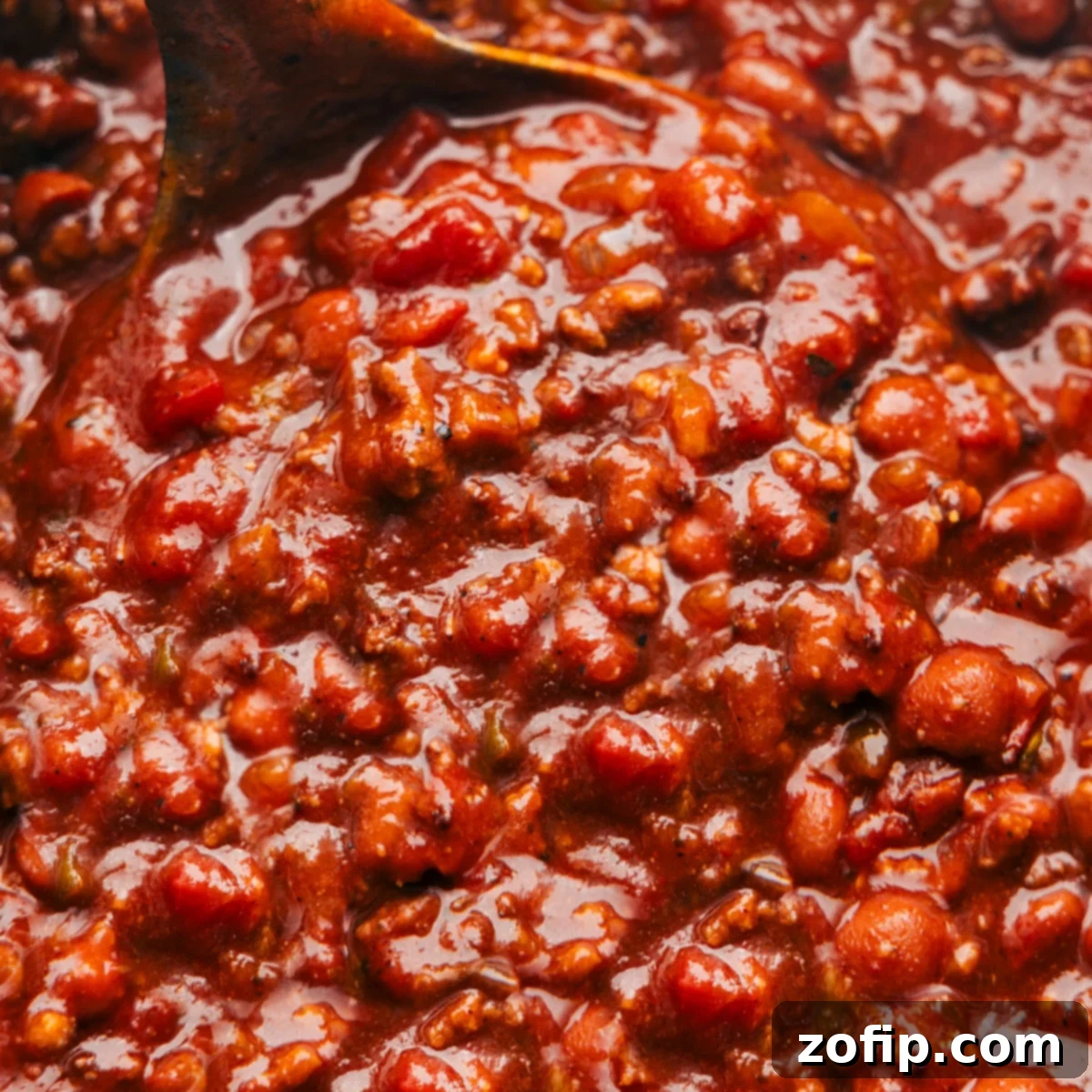 A hearty bowl of the best crockpot chili recipe, garnished with sour cream, cheese, and cilantro, ready to eat.