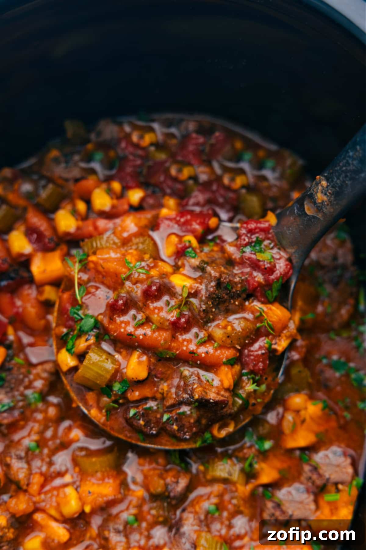A large ladle serving a generous portion of Sweet Potato Stew from a slow cooker into a bowl.