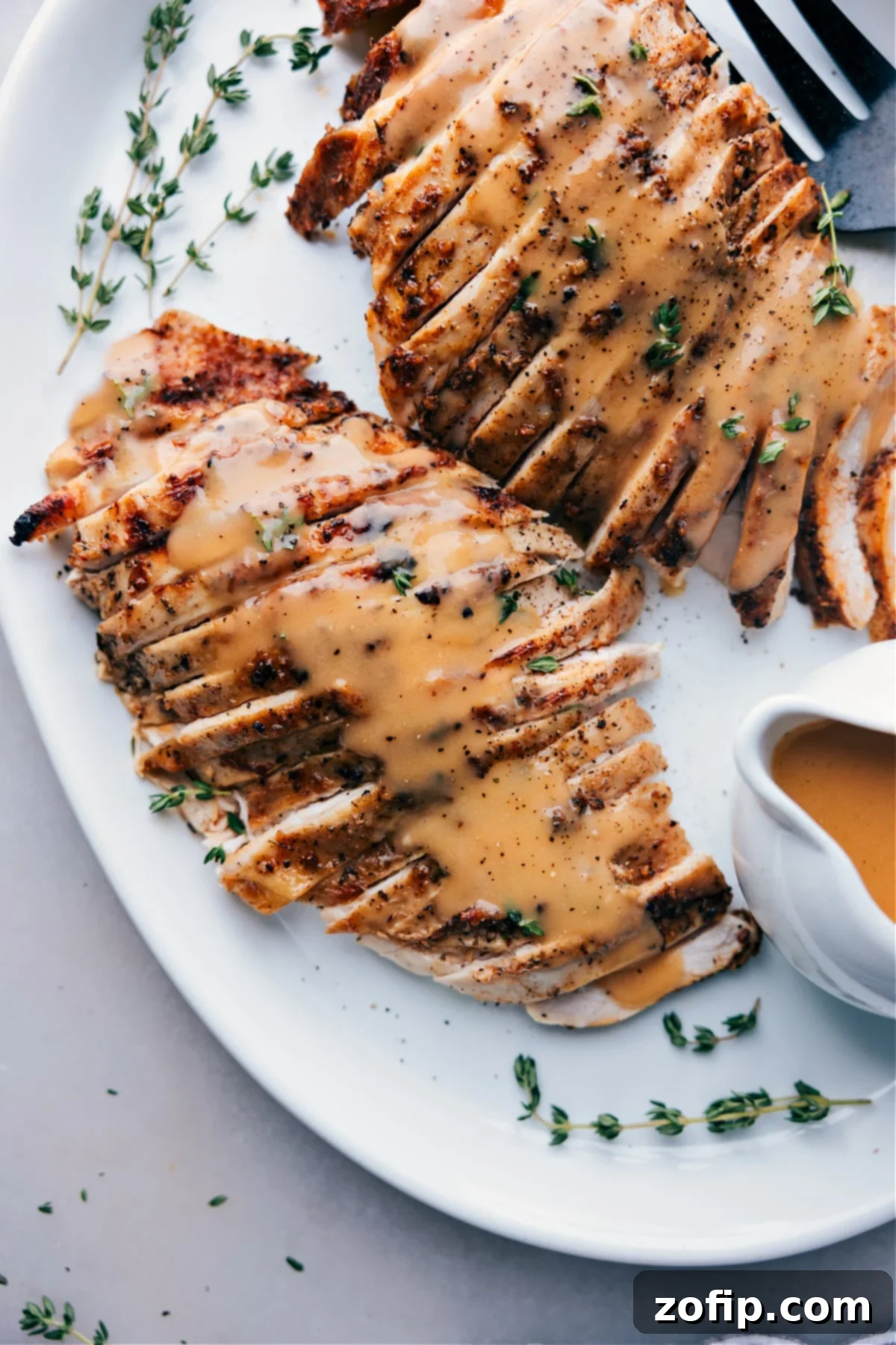 A beautifully cooked turkey breast, generously covered in a rich, homemade gravy, elegantly presented on a plate and ready to be enjoyed.