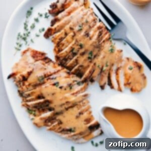 Sliced turkey breast cooked in a crockpot, served on a plate topped with gravy and garnished with fresh herbs.