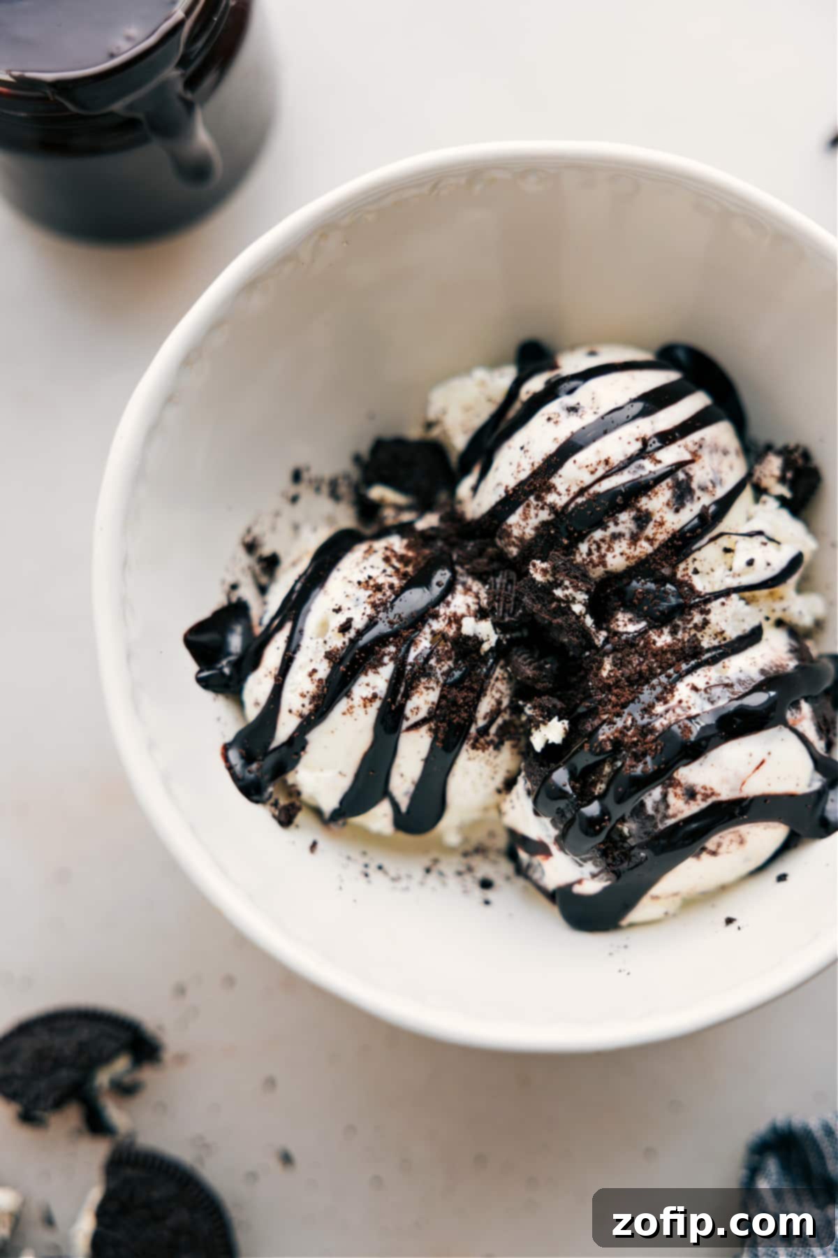 Lush, dark Hot Fudge Sauce generously drizzles over scoops of vanilla ice cream, ready to be enjoyed as a classic dessert.