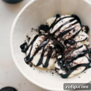 A serving of warm, rich hot fudge sauce in a small dish, with a spoon ready for drizzling, showcasing its thick and glossy texture.