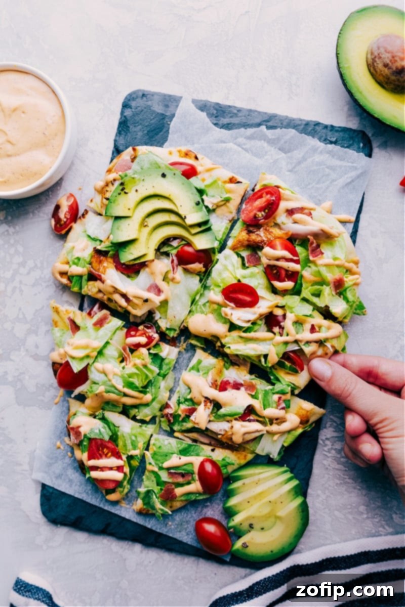 Chipotle Chicken Flatbread cut into slices, topped with fresh ingredients and drizzled with chipotle ranch, ready for serving.