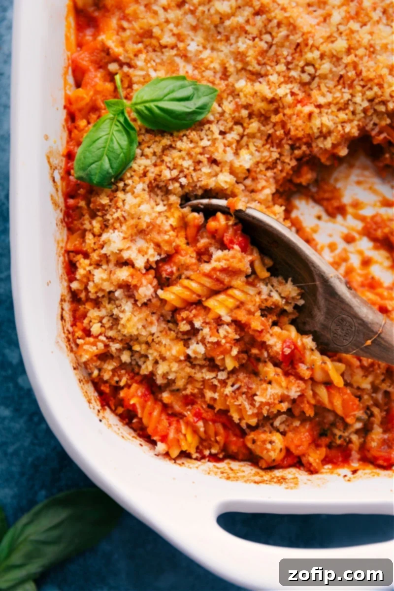 Overhead view of a baking dish filled with cheesy Chicken Parmesan Pasta, ready to serve.