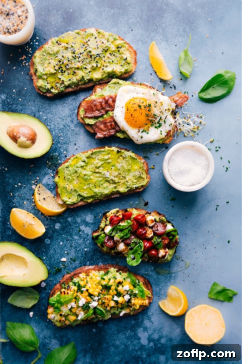 An overhead shot showcasing five different avocado toast variations, each uniquely topped and beautifully presented on a wooden board.