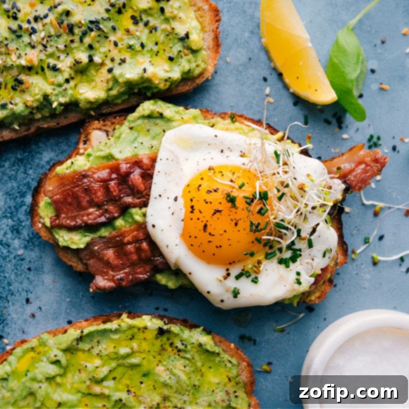 An overhead image of a delicious breakfast avocado toast, featuring a perfectly cooked sunny-side-up egg, crispy bacon, and a sprinkle of fresh chives on a bed of creamy avocado.