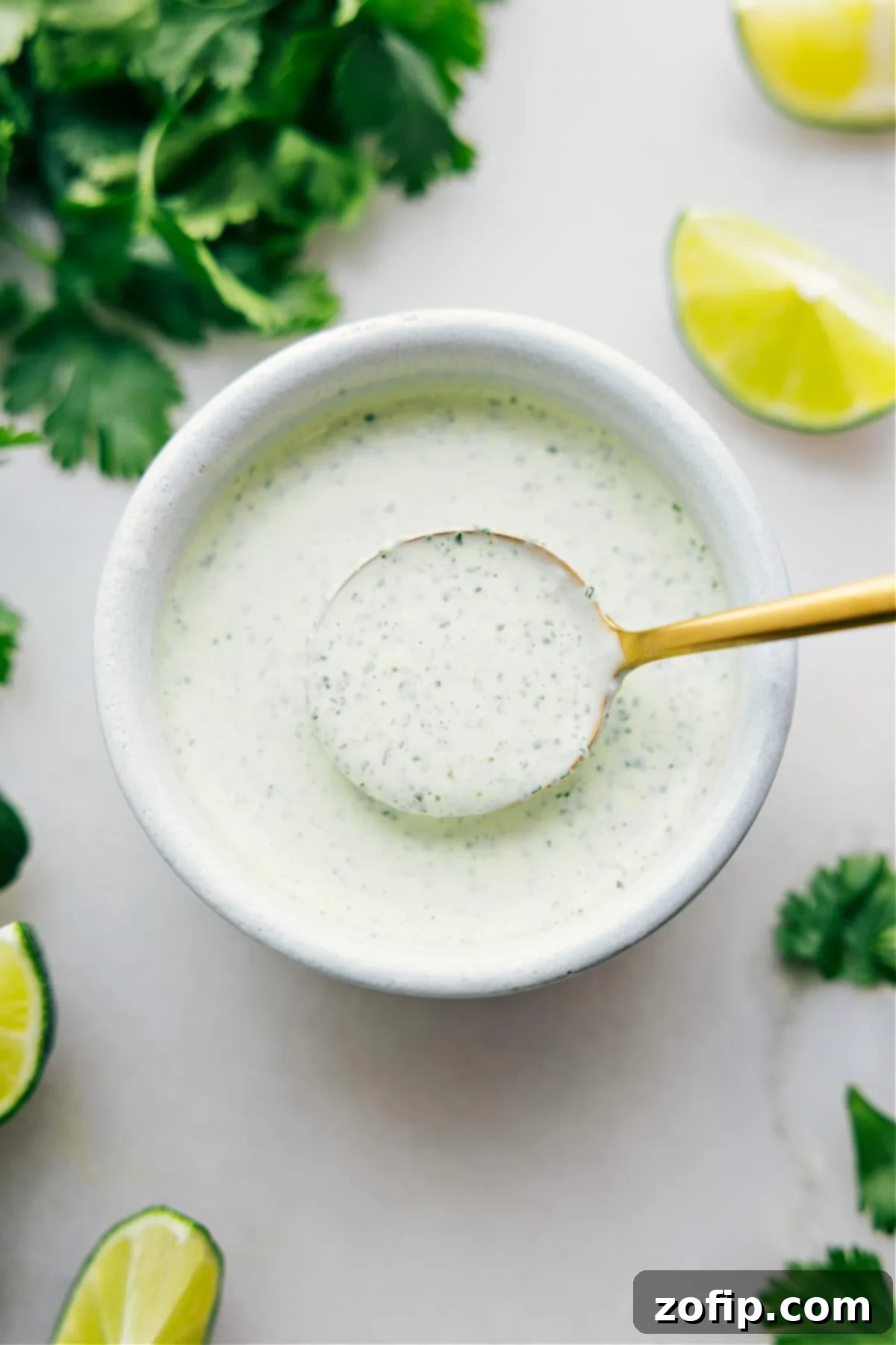 Cilantro Lime Sauce in a bowl with a spoonful coming up, highlighting its creamy texture.