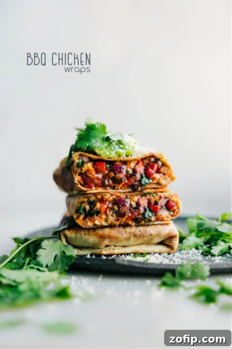 Zesty BBQ Chicken Roll-ups 2 Stacked crispy BBQ Chicken Wraps revealing a glimpse of the juicy chicken, melted cheese, and fresh vegetables inside.