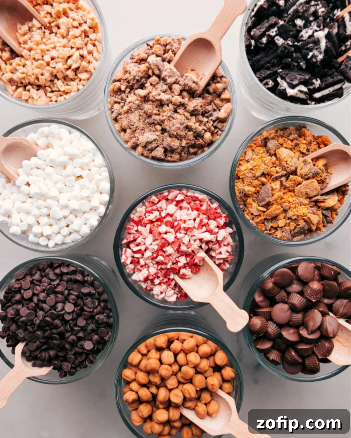 A diverse selection of hot chocolate toppings, including marshmallows, chocolate chips, and various sprinkles, neatly arranged in small glass bowls, ready for customization.