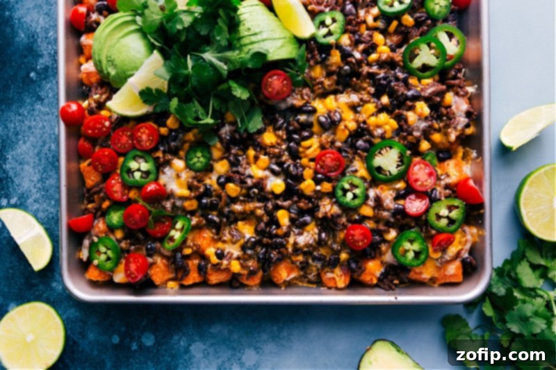 Overhead view of a tray piled high with golden Totchos, featuring seasoned ground beef, melted cheese, black beans, and corn, ready to be served.