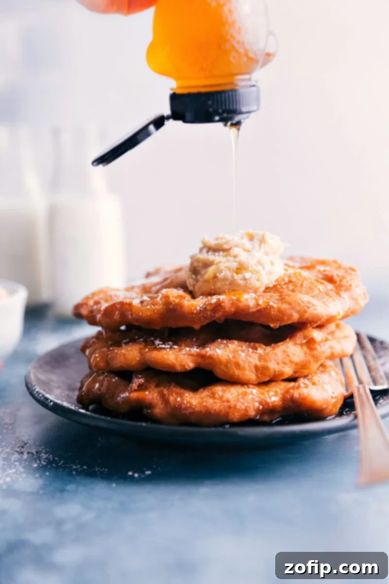 A close-up image of golden-brown Utah Scones being drizzled with honey, highlighting their puffy texture and delicious appearance.
