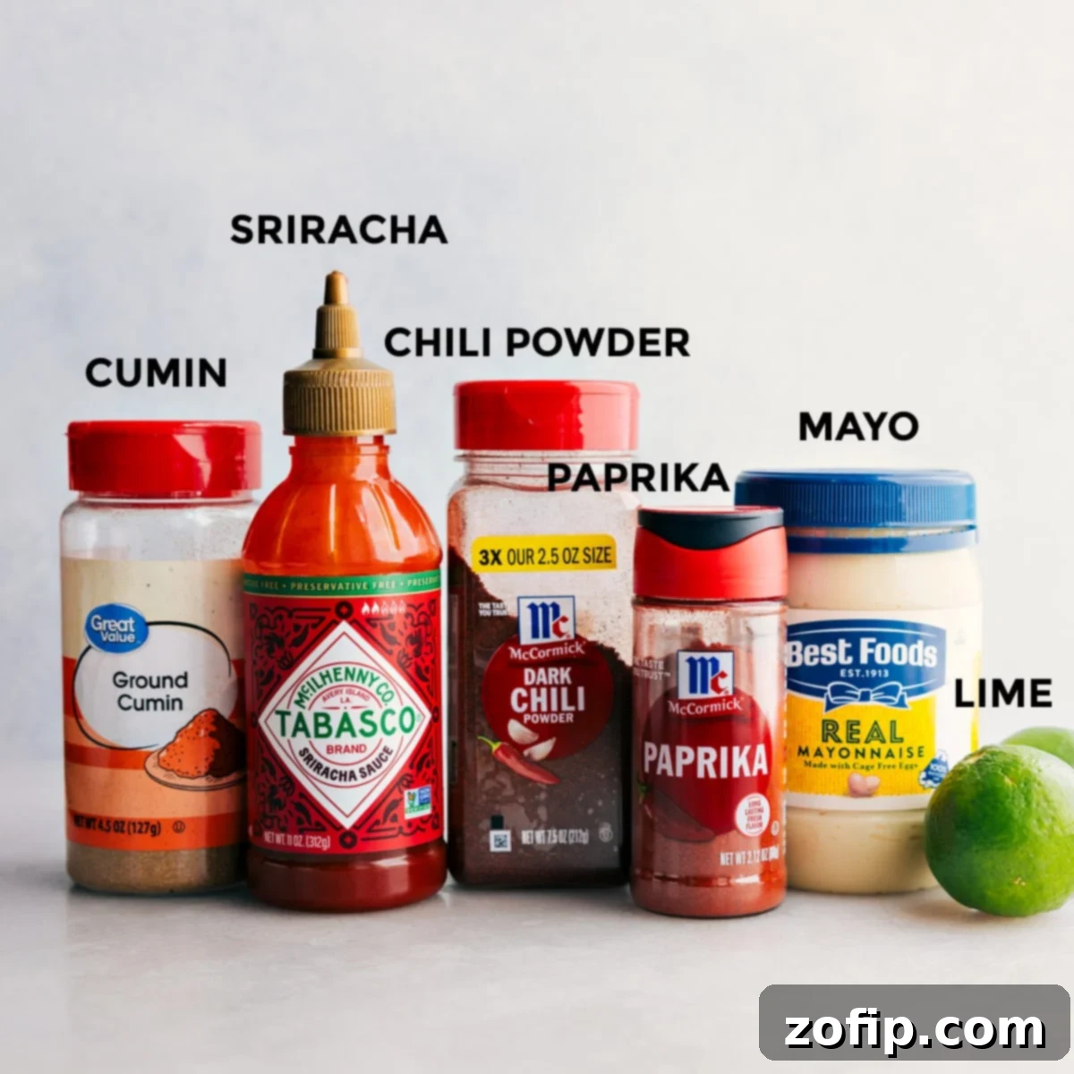 Easy Dressing For Mexican Street Corn Chicken Salad Recipe All the dressing ingredients including cumin, sriracha, chili powder, paprika, mayo, and limes prepped out for easy assembly.